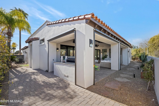 back of property with ceiling fan and a patio