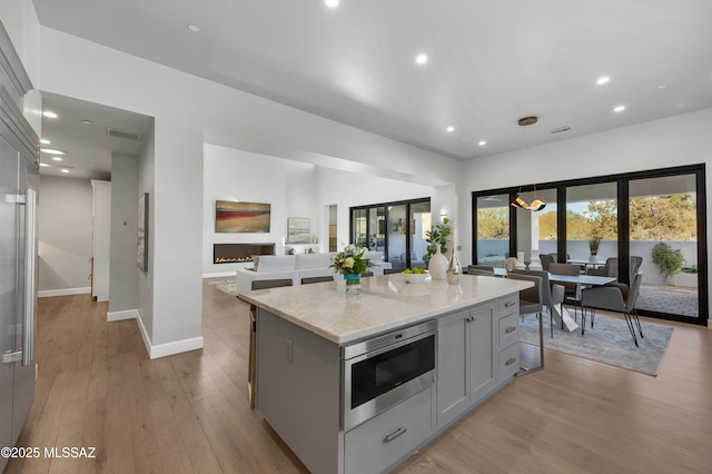 kitchen featuring stainless steel microwave, gray cabinetry, a breakfast bar, and a center island