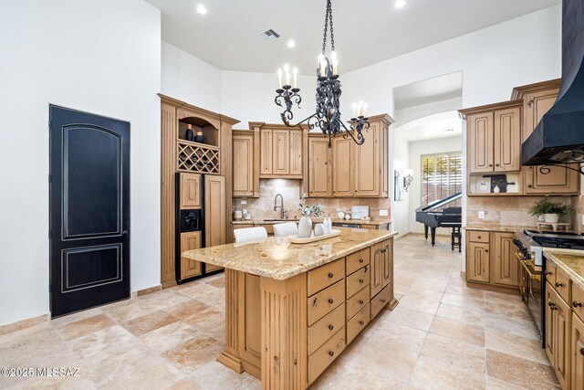 kitchen with visible vents, open shelves, wall chimney exhaust hood, high end appliances, and a kitchen island