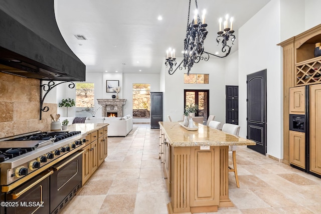 kitchen featuring a kitchen island, visible vents, a breakfast bar area, double oven range, and ventilation hood