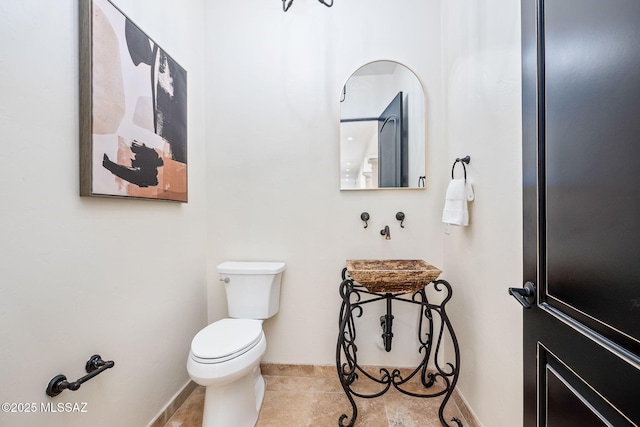 bathroom featuring toilet, baseboards, and tile patterned flooring