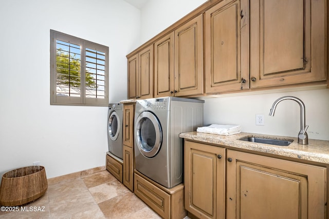 clothes washing area featuring cabinet space, baseboards, washing machine and dryer, and a sink