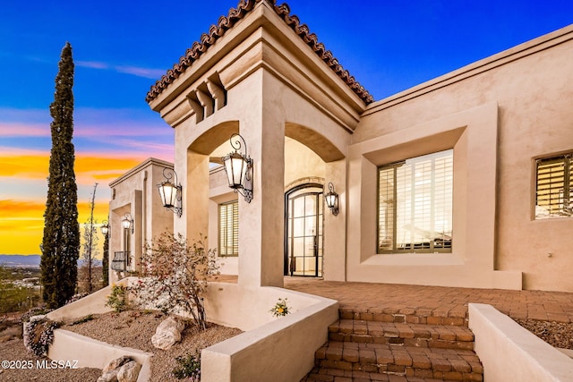 exterior entry at dusk featuring stucco siding