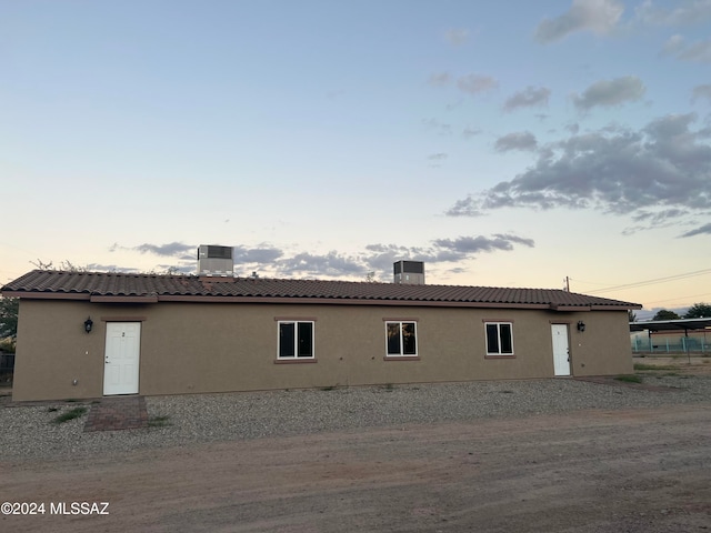 back house at dusk featuring central AC