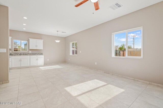 tiled empty room with ceiling fan and plenty of natural light