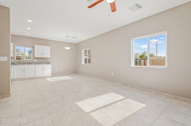 unfurnished living room with light tile patterned floors, ceiling fan, visible vents, and baseboards