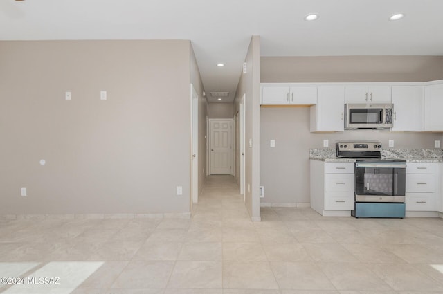 kitchen featuring appliances with stainless steel finishes, white cabinetry, and light stone countertops