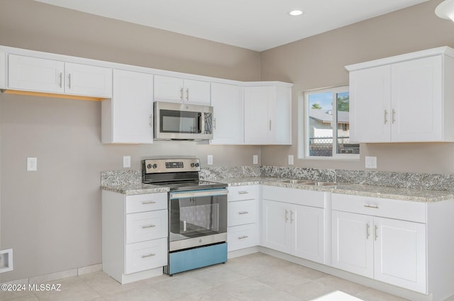 kitchen featuring light stone counters, appliances with stainless steel finishes, a sink, and white cabinetry