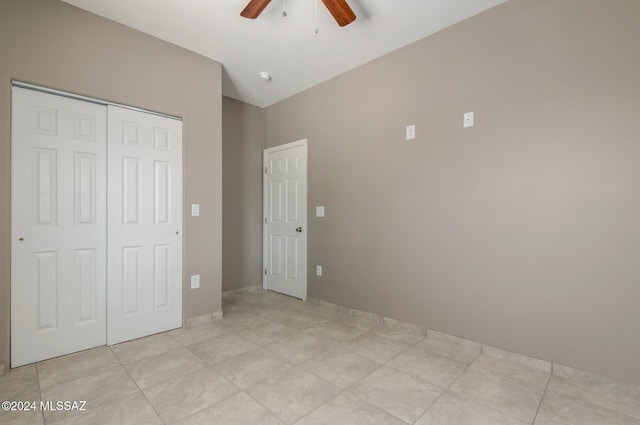 unfurnished bedroom featuring a ceiling fan, a closet, vaulted ceiling, and light tile patterned floors