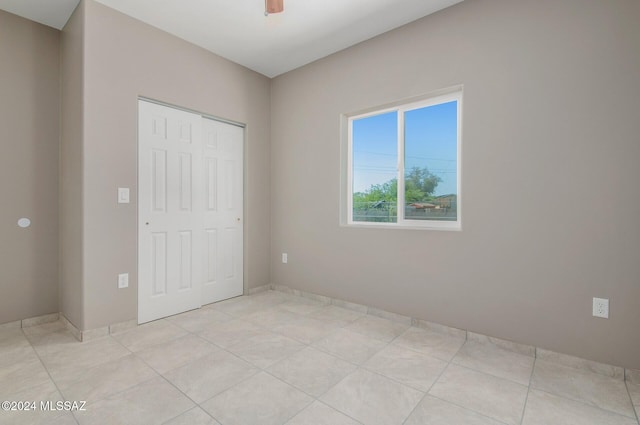 unfurnished bedroom with a ceiling fan, a closet, and light tile patterned flooring