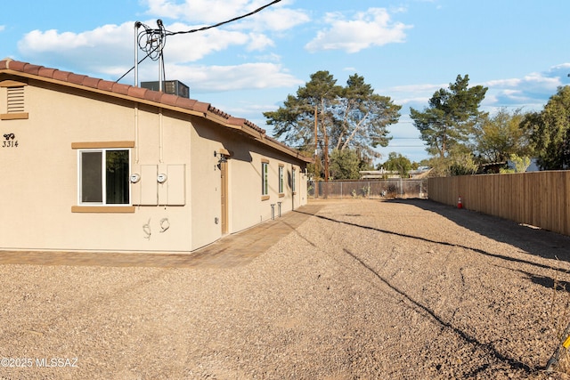 view of property exterior featuring a fenced backyard, a tile roof, and stucco siding