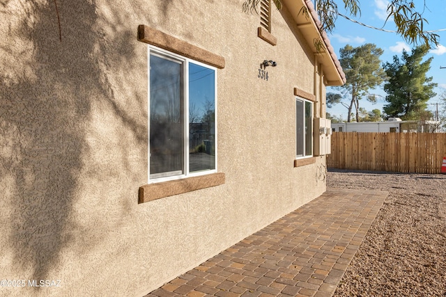 view of property exterior featuring a patio, fence, and stucco siding