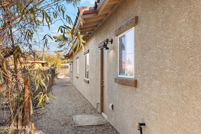 view of side of home with fence and stucco siding