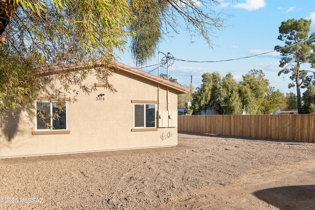 view of side of property featuring fence and stucco siding