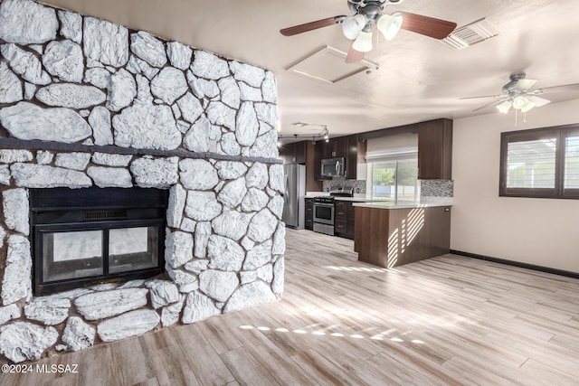 kitchen with stainless steel appliances, kitchen peninsula, decorative backsplash, dark brown cabinets, and light wood-type flooring