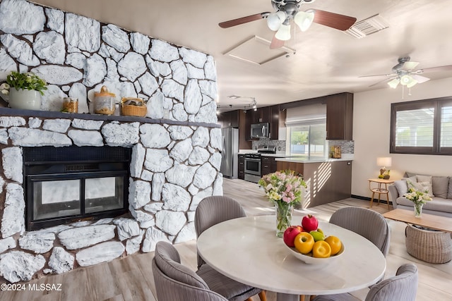 dining room with a stone fireplace and light wood-type flooring