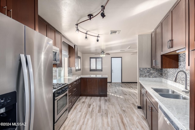 kitchen with appliances with stainless steel finishes, light wood-type flooring, tasteful backsplash, ceiling fan, and sink