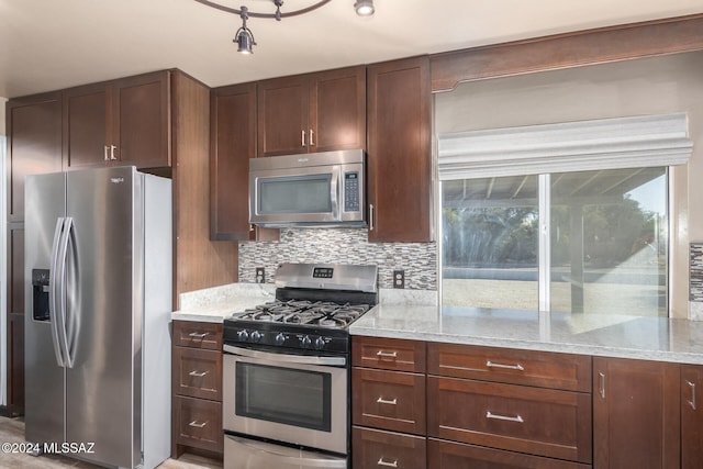 kitchen featuring backsplash, light stone counters, dark brown cabinets, and appliances with stainless steel finishes