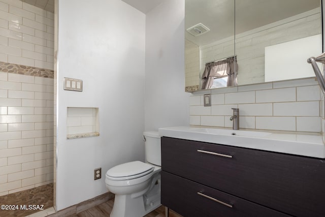 bathroom with vanity, a shower, backsplash, hardwood / wood-style flooring, and toilet