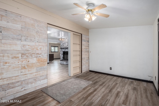 empty room featuring hardwood / wood-style floors, ceiling fan, and a fireplace