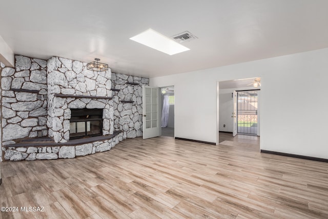 unfurnished living room with light hardwood / wood-style flooring, plenty of natural light, and a stone fireplace