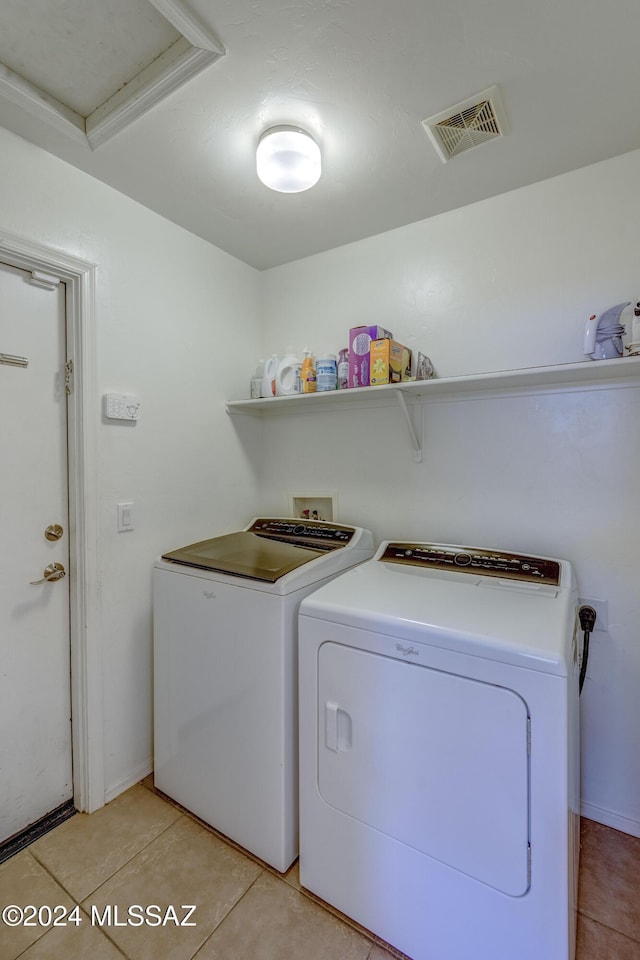 clothes washing area featuring light tile patterned floors and washer and clothes dryer