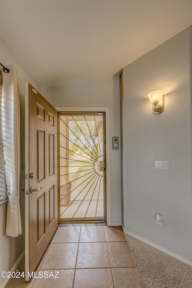 doorway with lofted ceiling and light tile patterned flooring