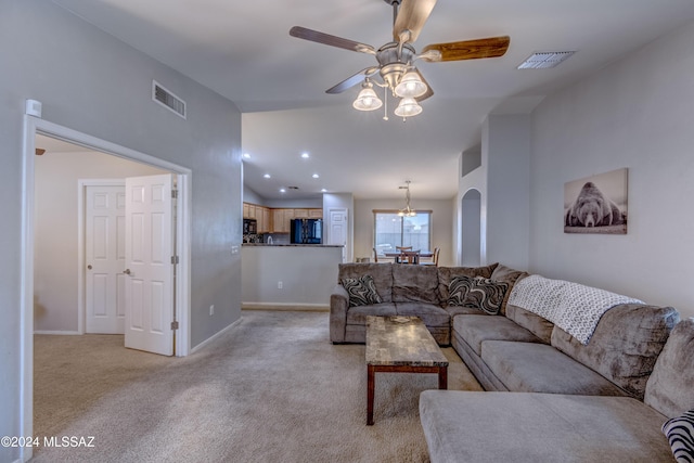 carpeted living room with ceiling fan with notable chandelier