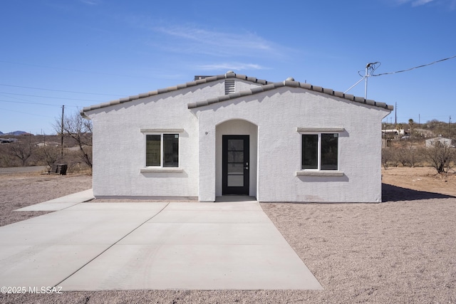 mediterranean / spanish house with a patio area, a tile roof, and stucco siding