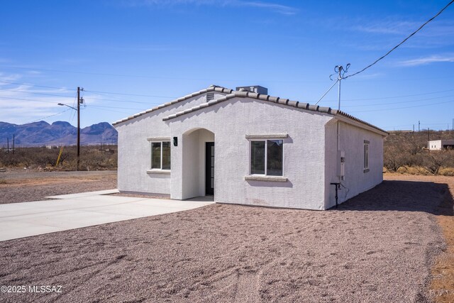 view of front facade featuring a patio area, a tiled roof, a mountain view, and stucco siding