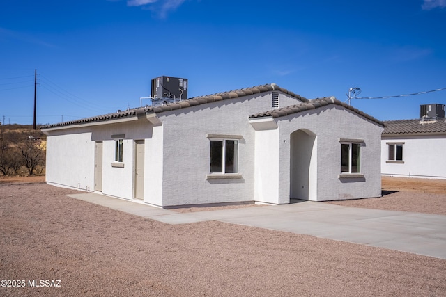 view of front of house featuring a tile roof, central AC unit, and stucco siding