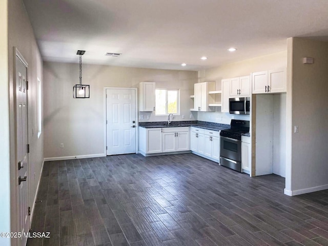 kitchen featuring white cabinets, dark countertops, appliances with stainless steel finishes, hanging light fixtures, and open shelves