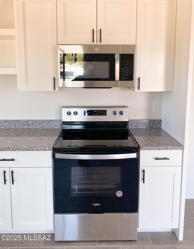 kitchen featuring appliances with stainless steel finishes, white cabinetry, light stone counters, and open shelves