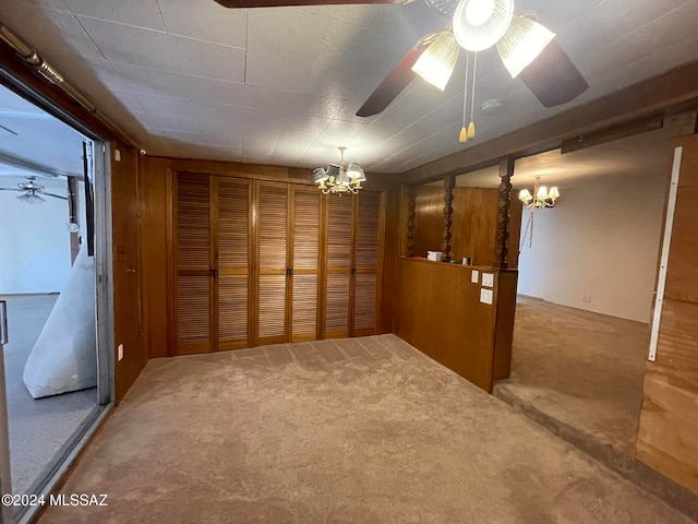 carpeted spare room featuring ceiling fan with notable chandelier