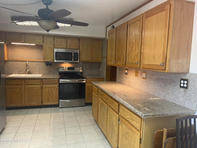 kitchen featuring sink, light tile patterned floors, appliances with stainless steel finishes, ceiling fan, and backsplash