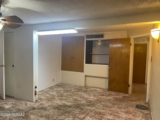 carpeted spare room with ceiling fan and a textured ceiling