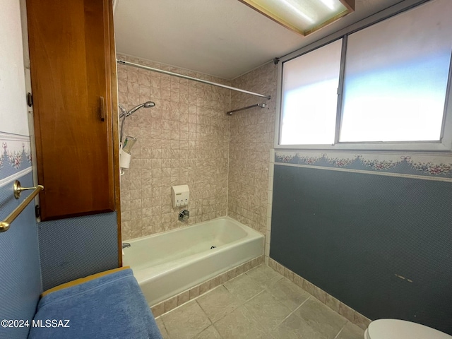 bathroom featuring tile patterned floors, toilet, and tiled shower / bath combo