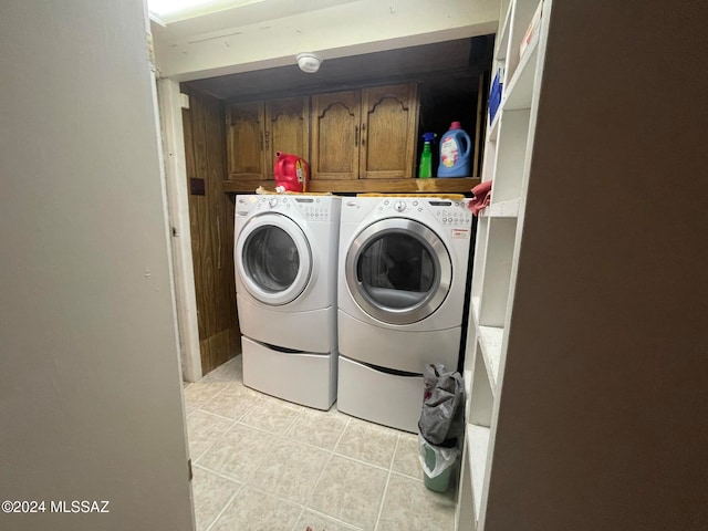 washroom with cabinets, light tile patterned floors, and washer and clothes dryer