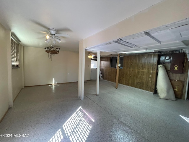 basement featuring ceiling fan and wood walls