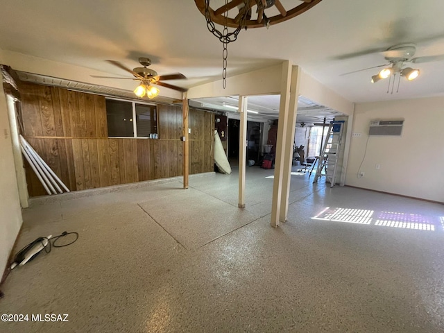 basement featuring a wall mounted air conditioner, ceiling fan, and wood walls