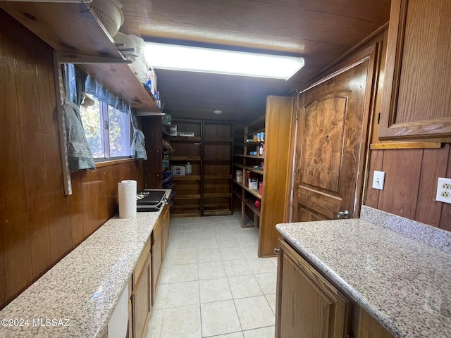 kitchen with light stone counters, wooden walls, and light tile patterned flooring