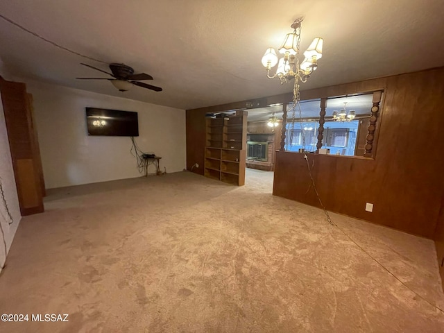 unfurnished living room with ceiling fan with notable chandelier and carpet flooring