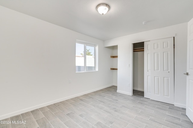 unfurnished bedroom with a closet, light wood finished floors, and baseboards