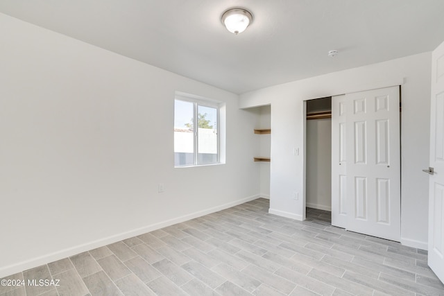 unfurnished bedroom featuring wood tiled floor, baseboards, and a closet