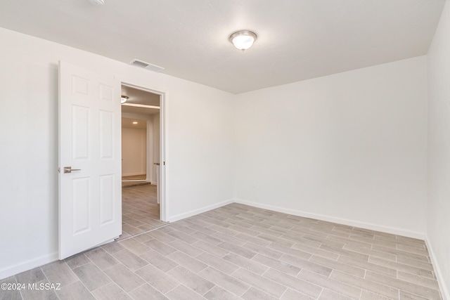 spare room featuring light wood finished floors, visible vents, and baseboards