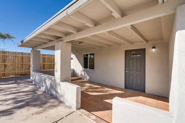 entrance to property with a patio, fence, and stucco siding