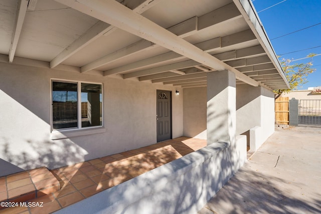 entrance to property with a patio, fence, and stucco siding