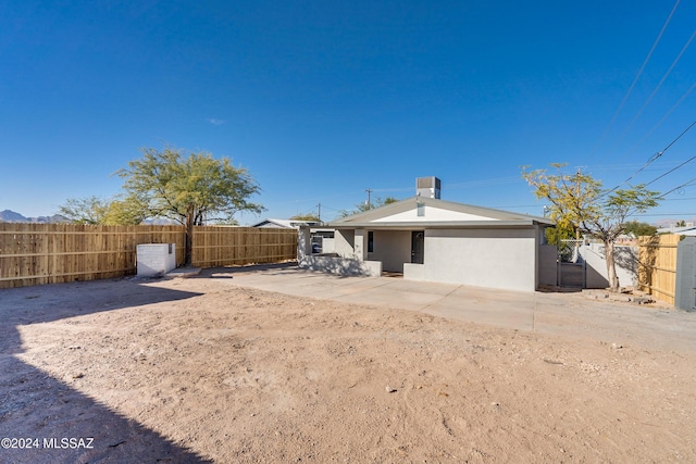 back of property with a fenced backyard, stucco siding, and central AC unit