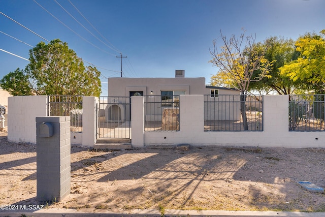 view of front facade with concrete block siding, a gate, and a fenced front yard