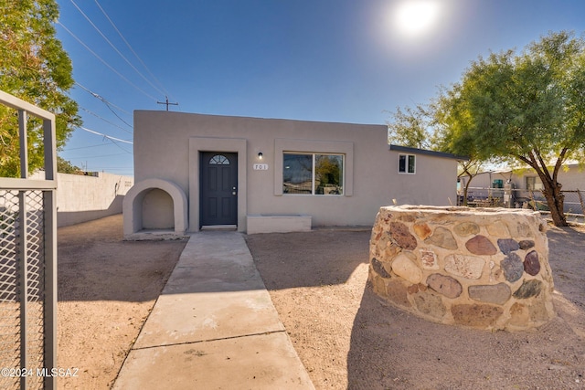pueblo-style house featuring fence and stucco siding